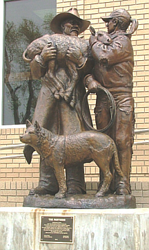 The Partners The Partners: bronze statue of a man and woman holding a sheep with a cattle dog in front of them